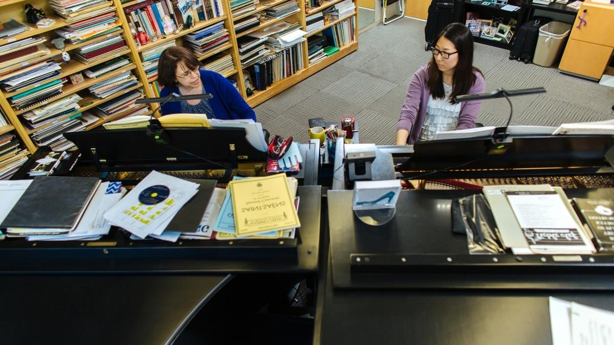 Two people playing pianos next to each other